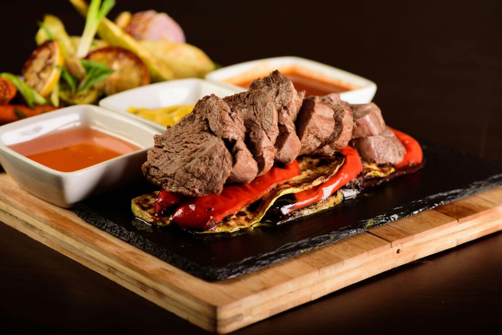 A delicious gourmet steak with grilled vegetables and various sauces. Perfectly styled for food photography.